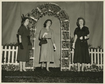 Three women pose on stage during the fashion show. Subjects unidentified. 