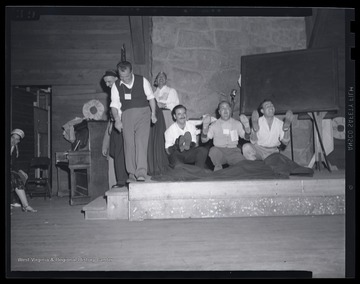 A group of men laugh as they lift the shoes that are covering their hands. Subjects unidentified. 