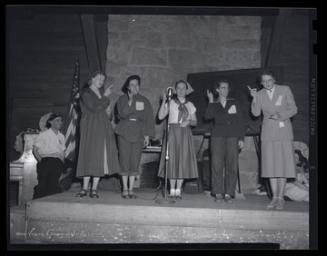 A group of women sing on stage at the leadership conference. Subjects unidentified. 