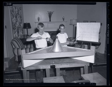 Two unidentified boys demonstrate a "practical brooder for pigs or lambs."