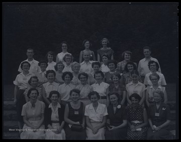 A group of unidentified men and women pose together for a group photo. 