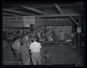 A group is gathered around the chicken feed exhibit. 