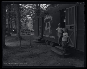 A young boy and girl stand outside of a trailer hosting the educational exhibit. Subjects unidentified. 