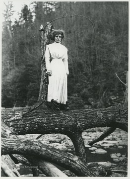 Woman posing on a fallen tree in Wyoming County, W. Va, likely near the Guyandotte River.  Original negative labeled "Mary".