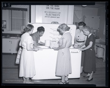 A group of women pull frozen food out from a large freezer. Subjects unidentified. 