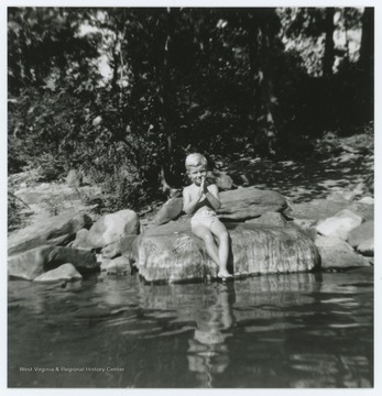 A unidentified young boy sits on a rock near Barger Springs, W. Va.