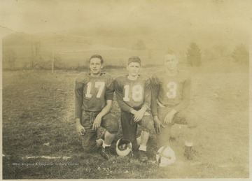 Frank Lambert (left), Richard Fraley (center), and Paul R. Cooper, Jr. (right) pose together in their football uniforms. 