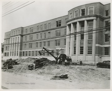 Exterior of Brooks Hall during construction.  Several workers and vehicles are visible.