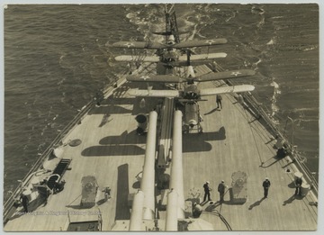 Crew members walk around the deck while the ship is at sea. 