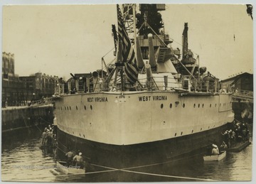 Crew members surround the battleship as its anchored near the dock. 