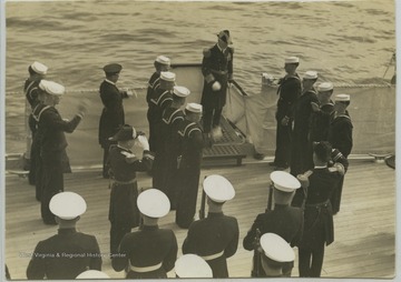 The admiral is greeted with a band and guard as he boards the ship.
