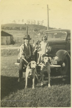 Claude Turner poses with his two dogs while his granddaughter Elizabeth Carole Butcher (b. 1934) balances on the automobile's bumper. Elizabeth later married a Weaver family member.