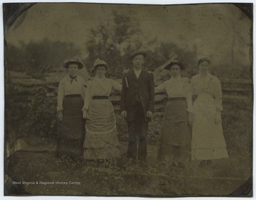 Four women and one man identified as Zinn family members pose together in front of a fence. 
