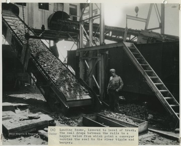 A coal miner at the Cedar Grove Collieries Inc. & Supply Co. mine observes as a loading boom drops coal between the rails into a hopper, which is carried by a conveyor to the river tipple and barges. 