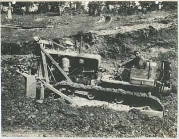 An unidentified man works a D-7 caterpillar bulldozer to push coal out of the way. 