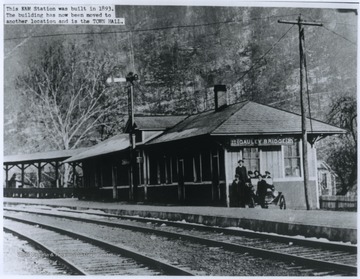 A group of men wait by a car parked beside the Kanawha & Michigan Railroad station. The station was built in 1893.