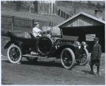 A man sits behind the wheel of a 1912 Buick model. 