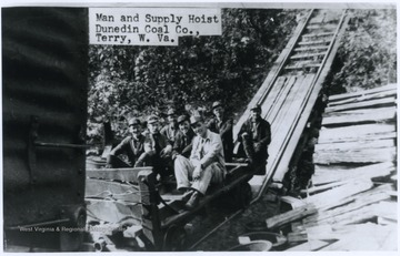 A group of miners sit on the hoist cart. 