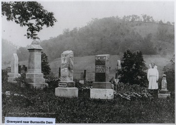 A young girl is standing by a grave marker in what is now known as the Quickle Cemetery in Burnsville, W. Va.