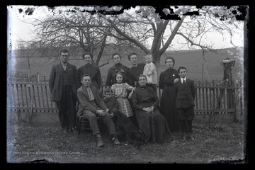 A multi-generational family poses in front of a picket fence. Subjects unidentified. 