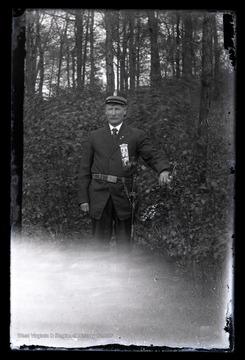 An unidentified man belonging to Independent Order of Odd Fellow (IOOF) organization poses in a forest. 