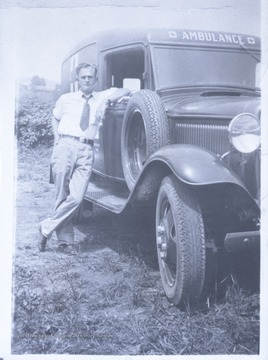 An unidentified man leans against the vehicle with his arm rested in the open window. The name on the envelope that this photograph's negative is contained in is labeled "Muriel Lanham."