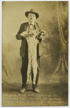 Crookshanks, father of Maggie Crookshanks, poses with the largest wild cat caught in Nicholas County, weighing 27 pounds and 4 feet, 7 inches in length. 