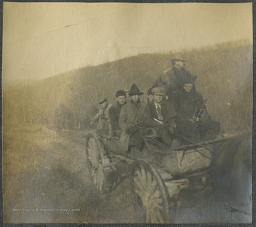 A group of unidentified men travel together on a horse-drawn vehicle.This photograph is found in a scrapbook documenting the survey for the B. & O. Railroad in West Virginia and surrounding states. 