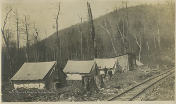 The surveyors camp is set beside railroad tracks. The tents are, left to right, No. 3, No. 2, No. 1, and the Cooks tent.  The wooden building is the Mess hall.  The camp was "our last and best camp."This photograph is found in a scrapbook documenting the survey for the Baltimore and Ohio Railroad in West Virginia and surrounding states. 
