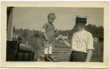 Raymond, standing on the car, is likely around age one.