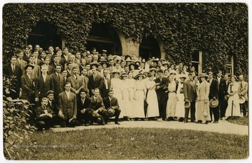 A large group of people pose in front of Commencement Hall at WVU.