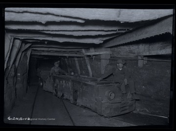 Two men ride on the engine hauling empty coal cars.
