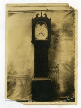 Photo taken outside a home, against a painted backdroup.  Back of photo reads: "Blake Clock, given to me winter 1923."