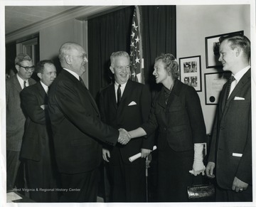 Text on the back reads, "Swearing in ceremony of Under Secretary of the Army Stephen Ailes, held at the Pentagon, Washington, D. C.  Former Secretary of Defense Louis A. Johnson congratulates Under Secretary of the Army and Mrs. Ailes." 