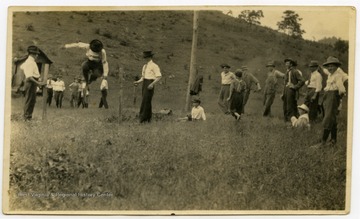 Boys and girls club recreational activities.  A boy on the left is performing a high jump over a rope.