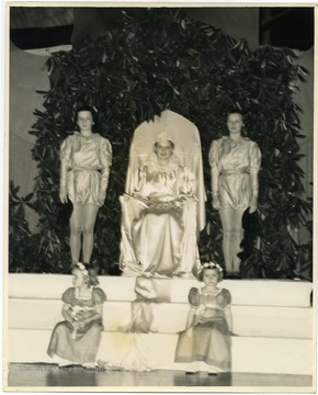 "Miss Helen Baker reigned, in a Rhododendron bower, as the Queen of the May at West Virginia University's annual festival which was part of Greater West Virginia Week activities. She is a member of Alpha Xi Delta, a candidate for beauty queen, and a member of the university social committee."