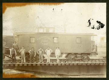 The workers and caboose belong to the Chesapeake and Ohio Railroad Company.