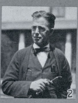 Photograph from "The Hardwood Bark," a periodical journal published by the W. M. Ritter Lumber company in the interest of its employees.This image is on a page with several other photos titled "Snapshots From Hurley." It depicts a man in a suit, bow tie, and glasses holding a smoking pipe. The caption for this photo reads:"2. W. A. Lawrence, Pay Roll Clerk at Hurley, and an Old Timer."