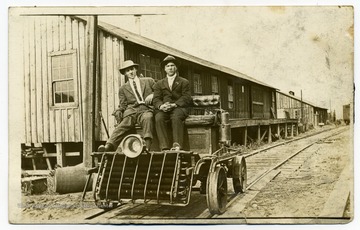 Two members of the Army Corps of Engineers pose for a photo on a railroad work car.